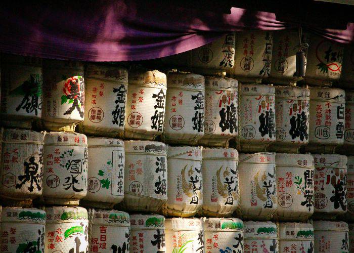 A wall of ceremonial sake donations in the sunlight at a Japanese shrine.